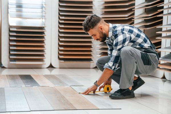 Man in grey uniform is with parquet indoors.
